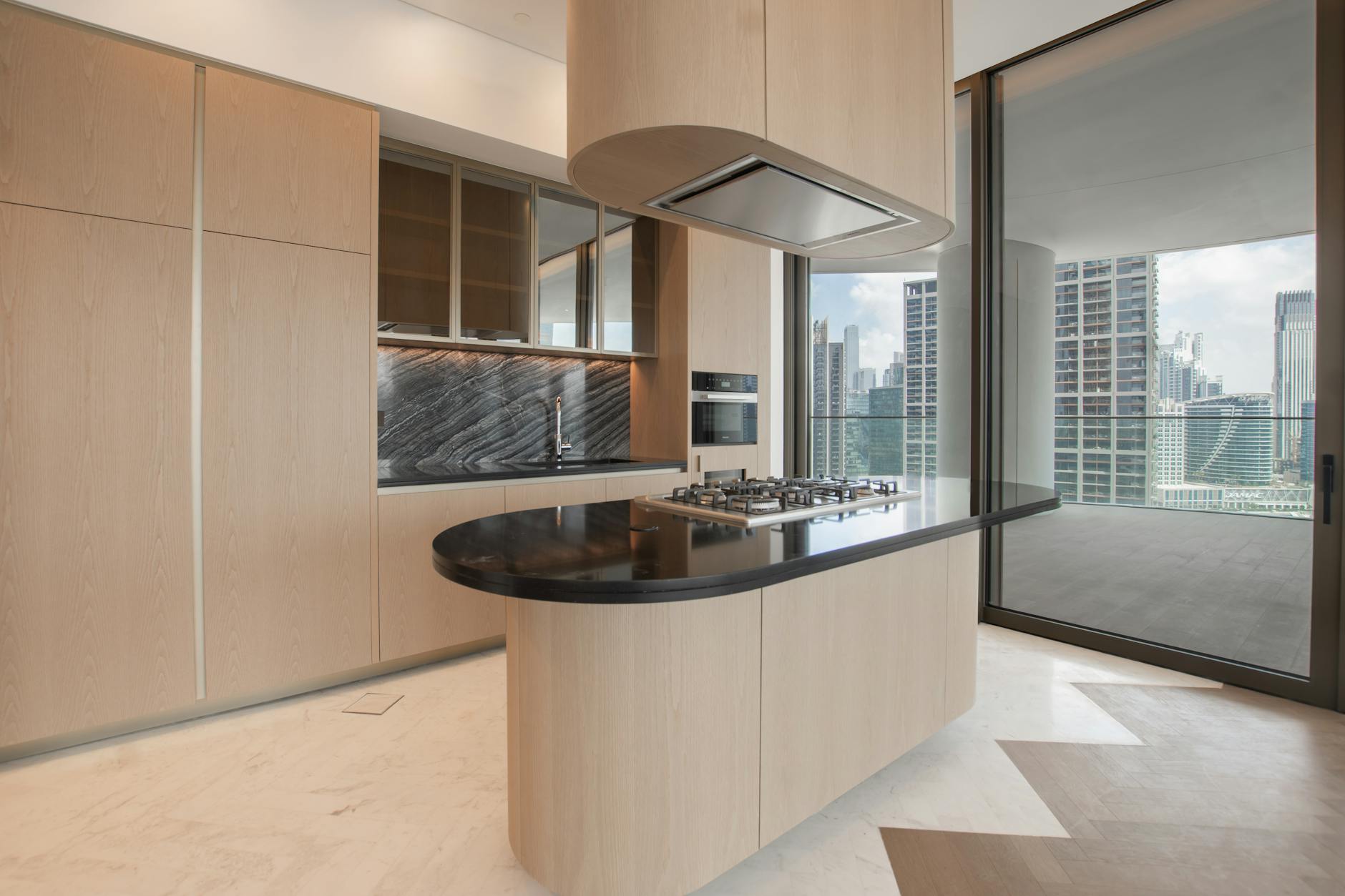 Jem Prime Limited Services. Sleek modern kitchen featuring an island and city skyline view.