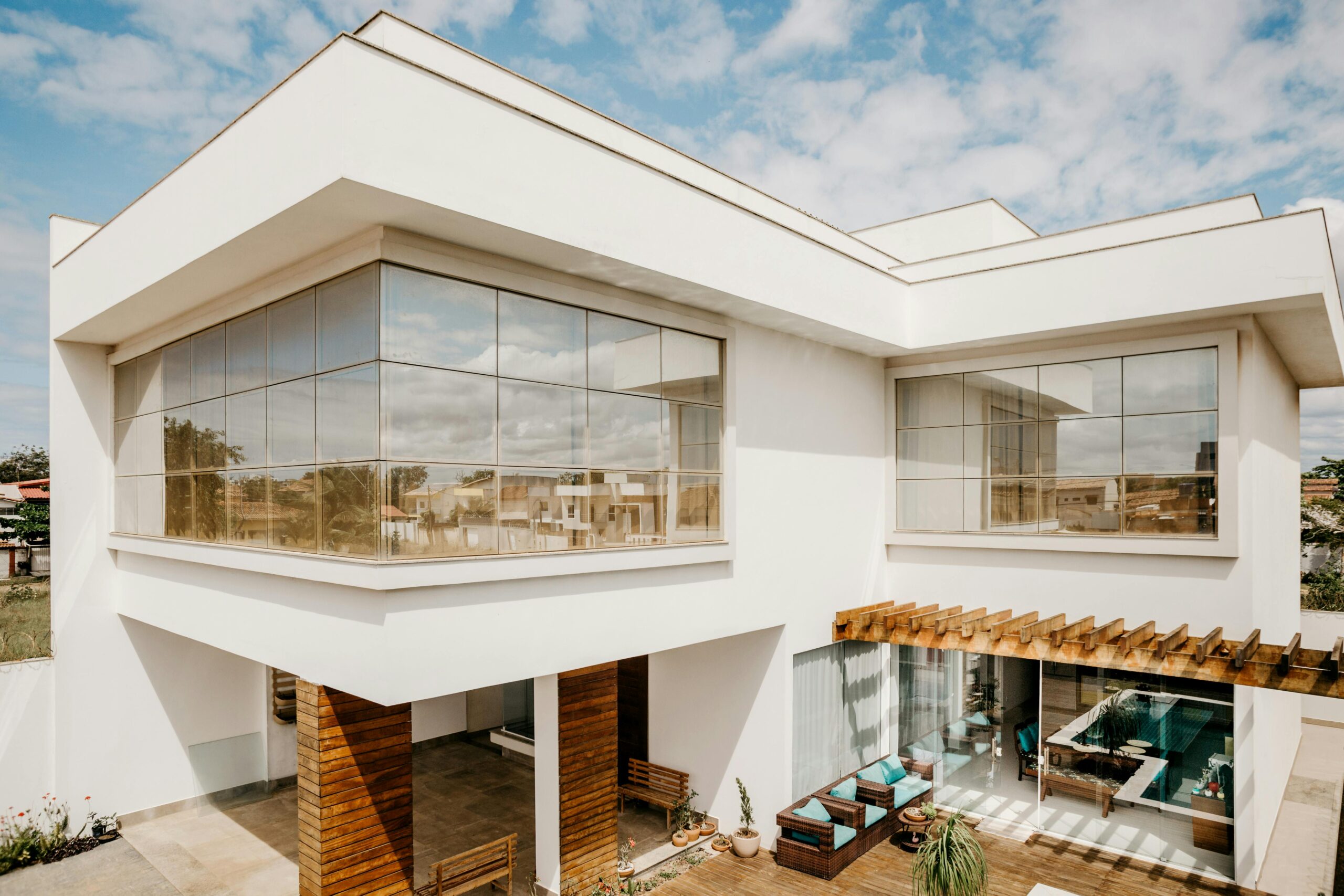 Jem Prime Limited Services. Exterior of contemporary cottage with large windows and stylish terrace against cloudy blue sky